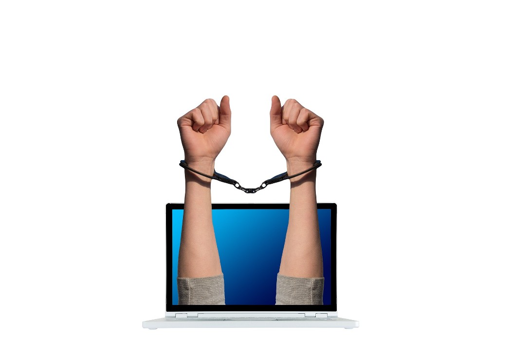 ruke izlaze iz laptopa zavezane lisicama