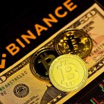 natpis binance ispod njega novcanica dolara i kovanica bitcoina